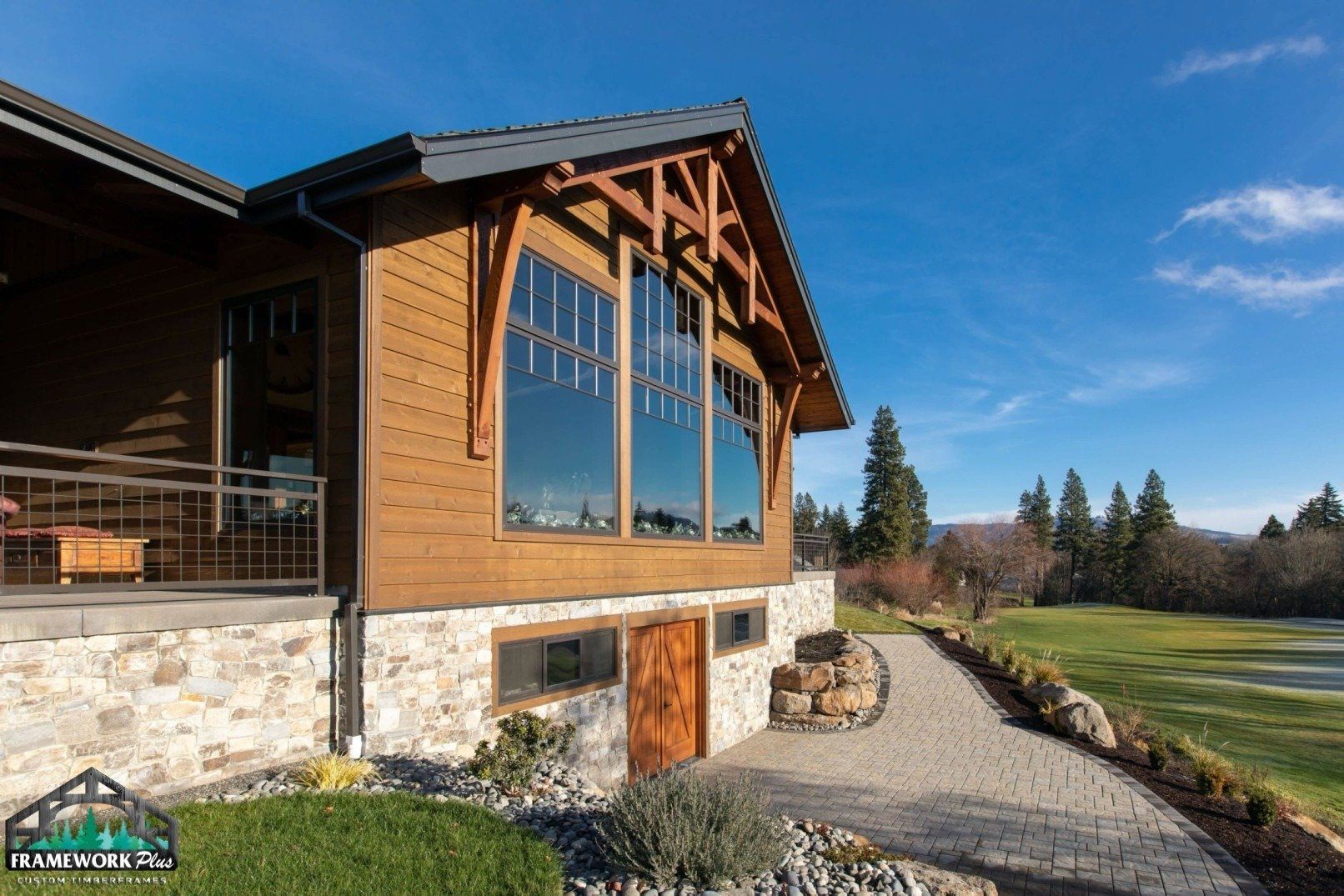 A large wooden house with a lot of windows is sitting next to a golf course.