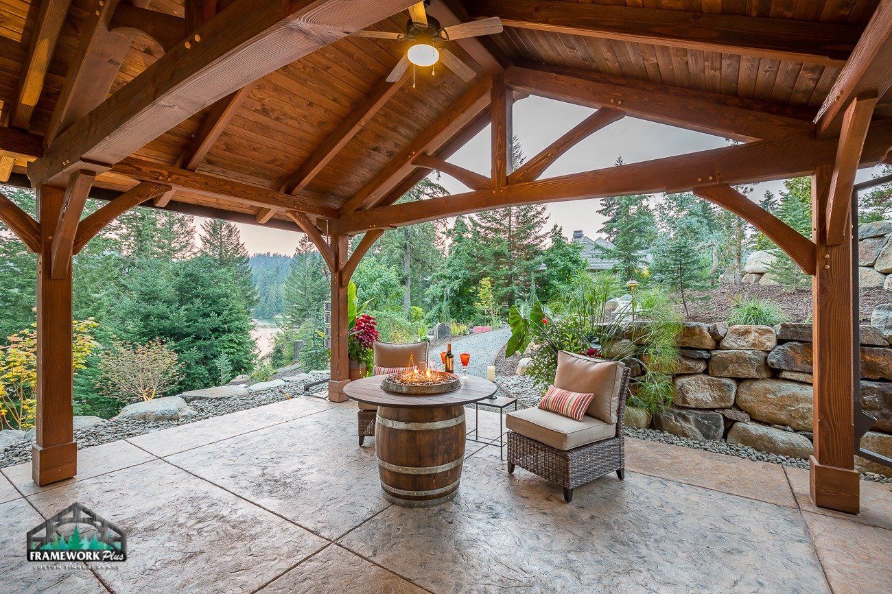 A wooden gazebo with a table and chairs underneath it.
