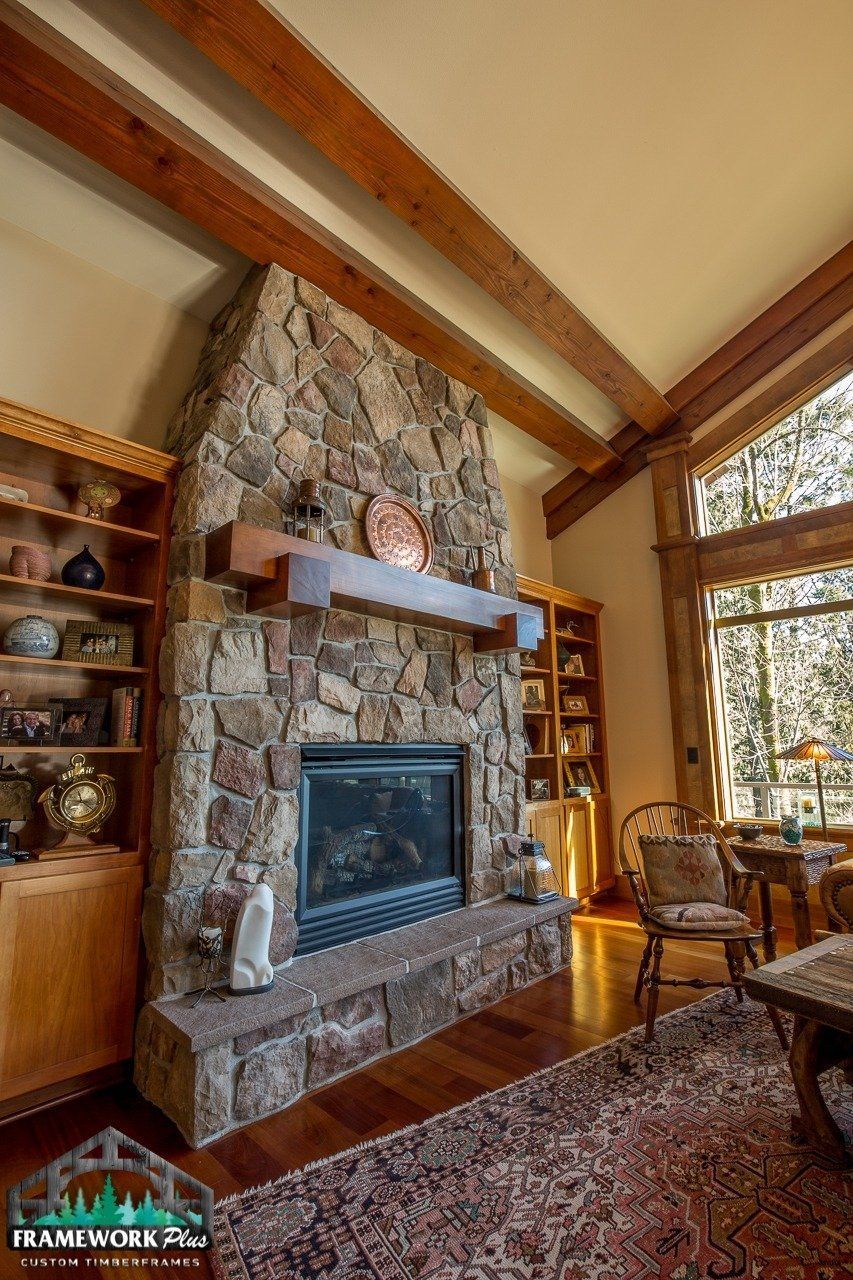 A living room with a large stone fireplace and wooden beams.