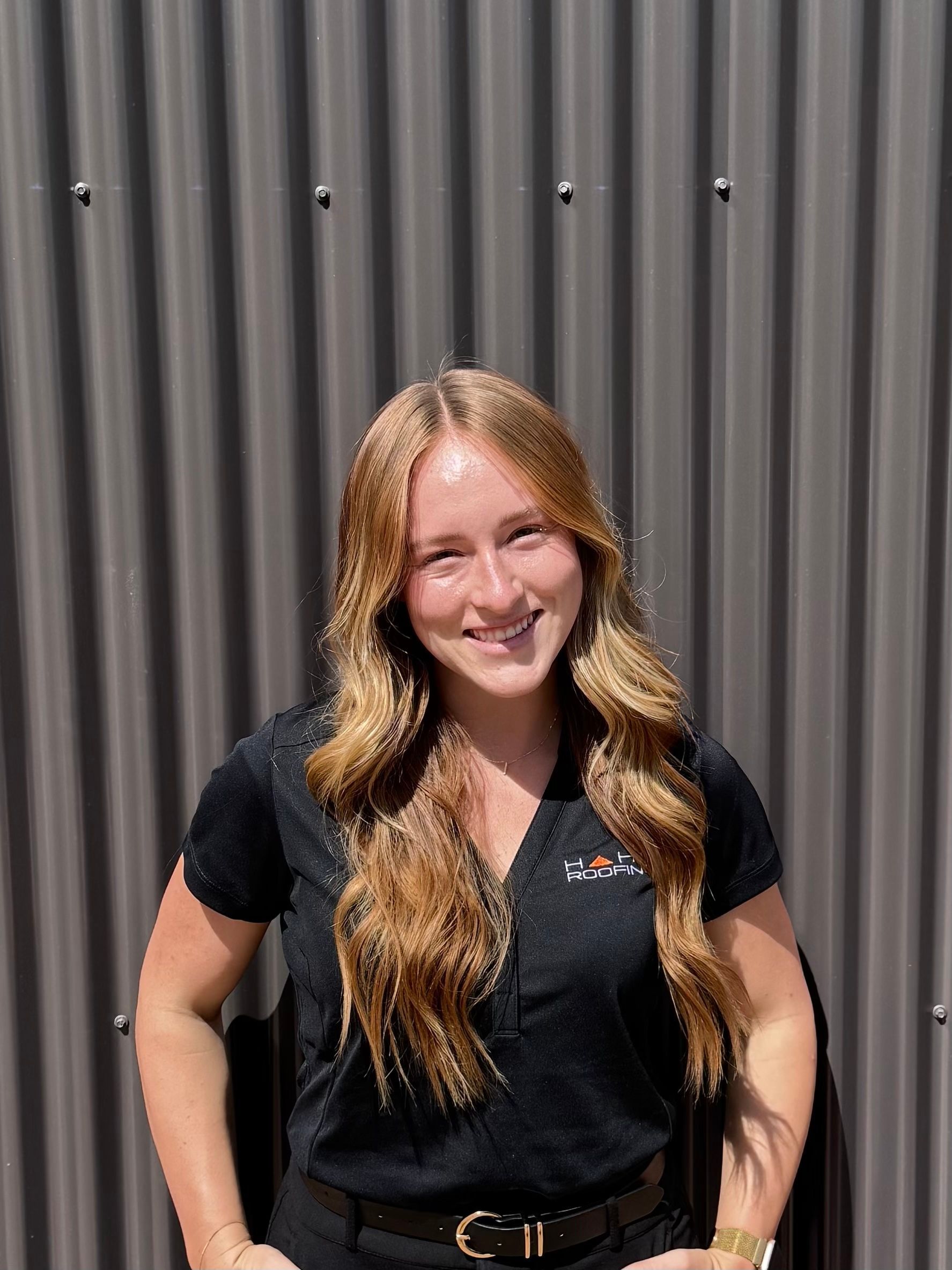 Man in sunglasses and hat driving a forklift outdoors, smiling.
