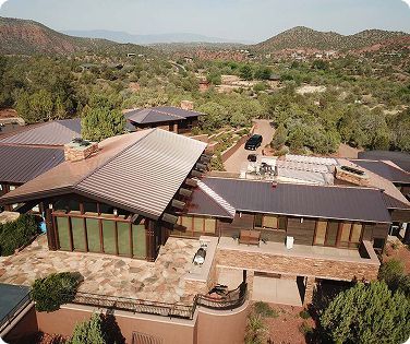 Aerial view of a complex of buildings with copper-colored roofs and a mountainous, desert landscape.