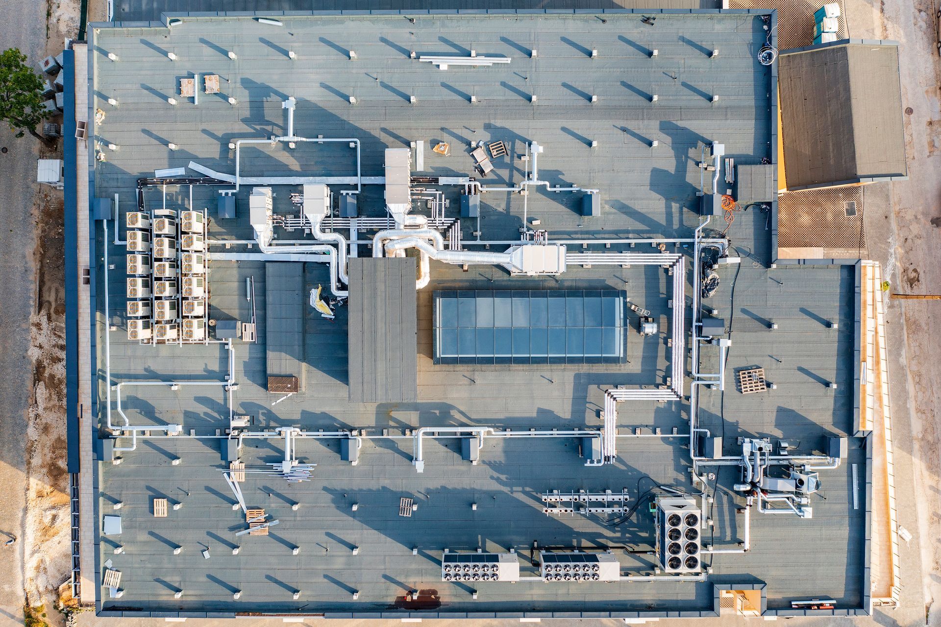 Overhead view of a building's flat roof with HVAC equipment, including pipes, vents, and units.