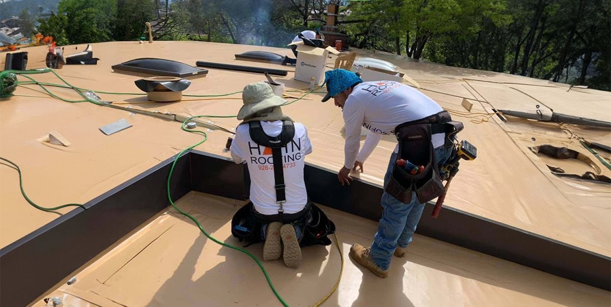 Team of roofing contractors installing a flat roof membrane