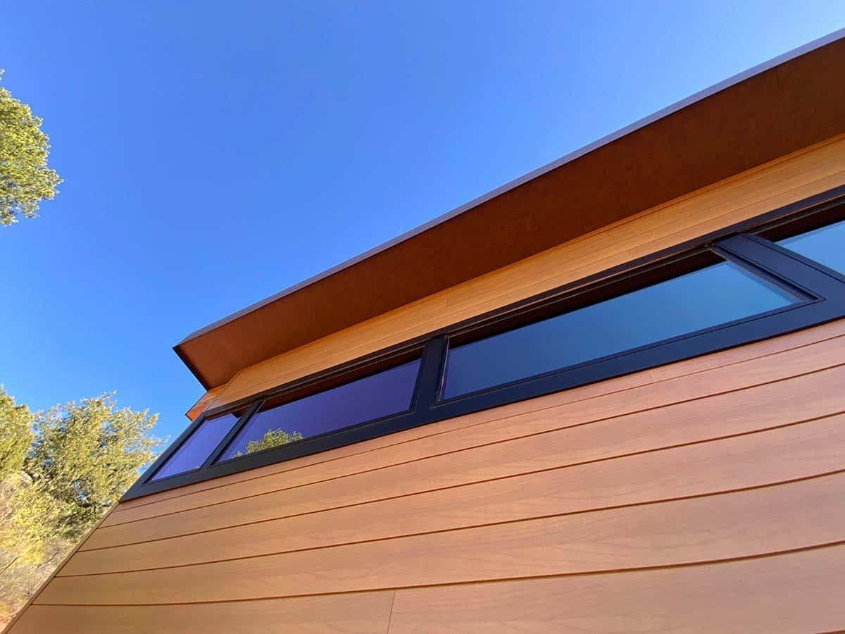 Wooden building with dark windows under a blue sky.