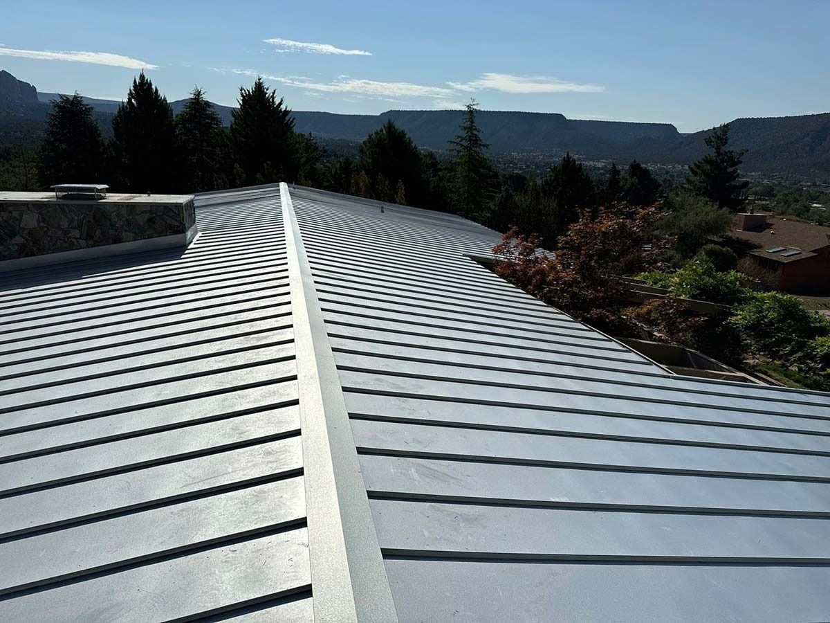 Silver metal roof with linear design, mountain and tree background.