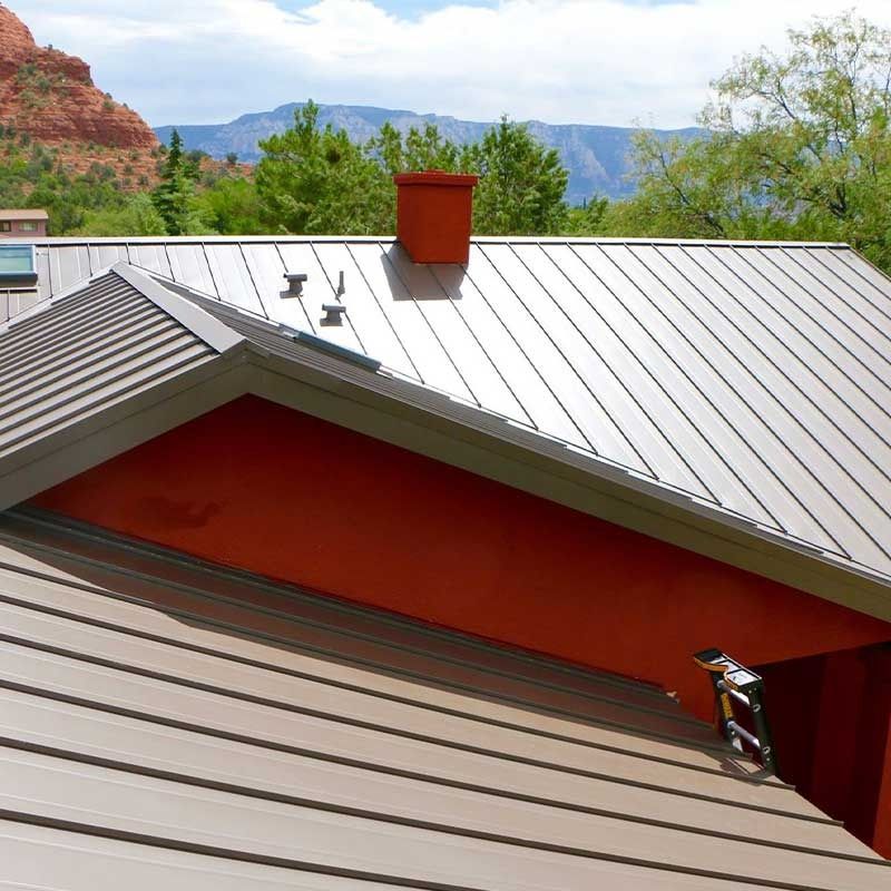 Metal roof with red trim and chimney, set against a mountainous backdrop.