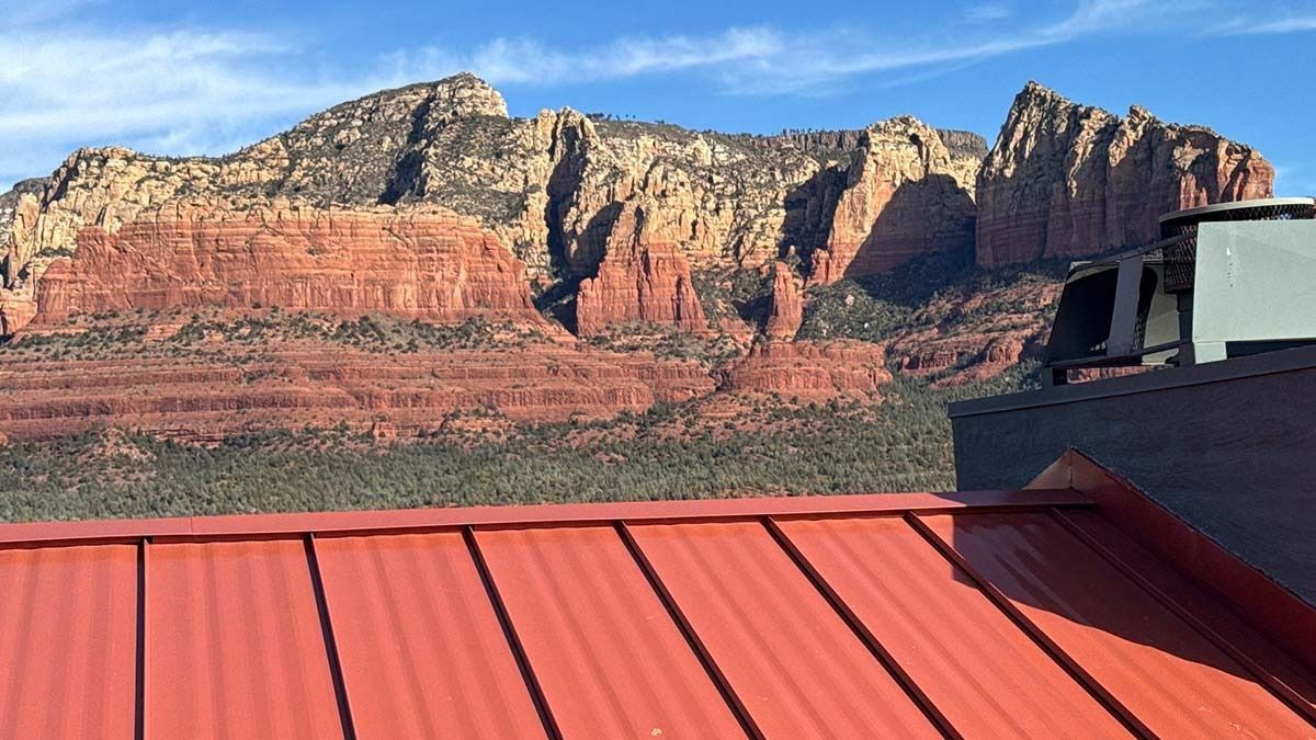 Red metal roof with a backdrop of red rock mountains and a blue sky.