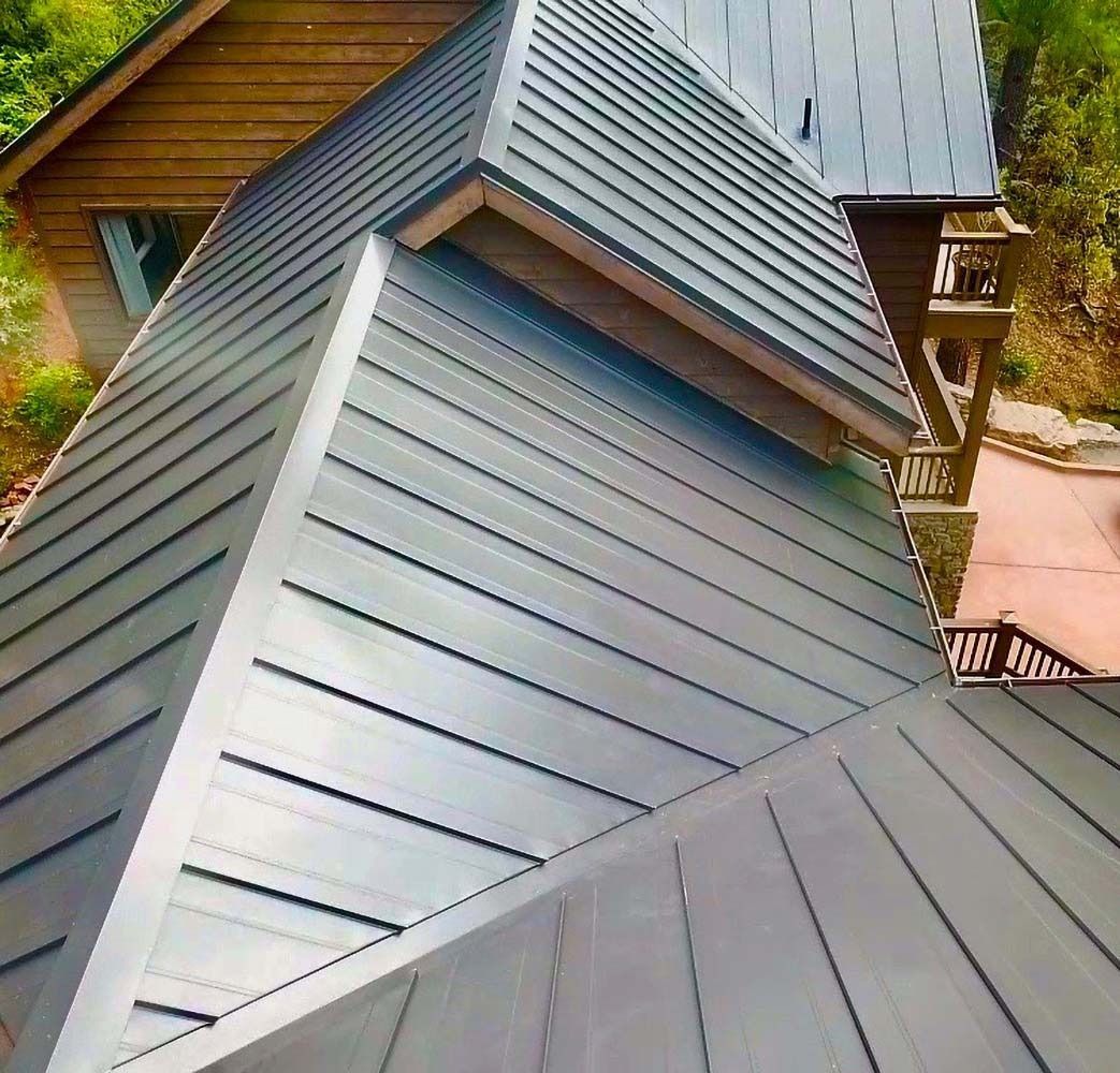 Metal roof of a multi-level wooden house; angled view, gray and brown tones.