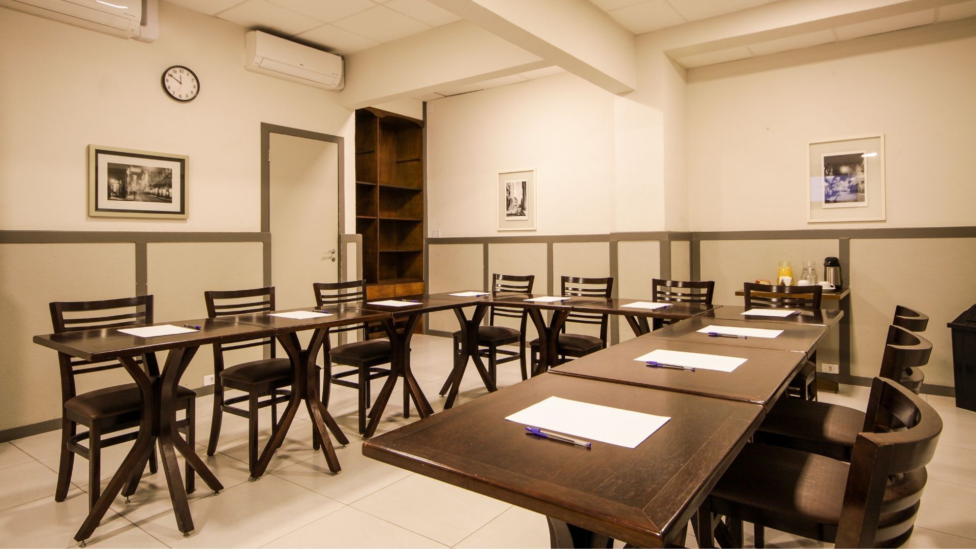 Uma sala de conferências com mesas e cadeiras e um relógio na parede.
