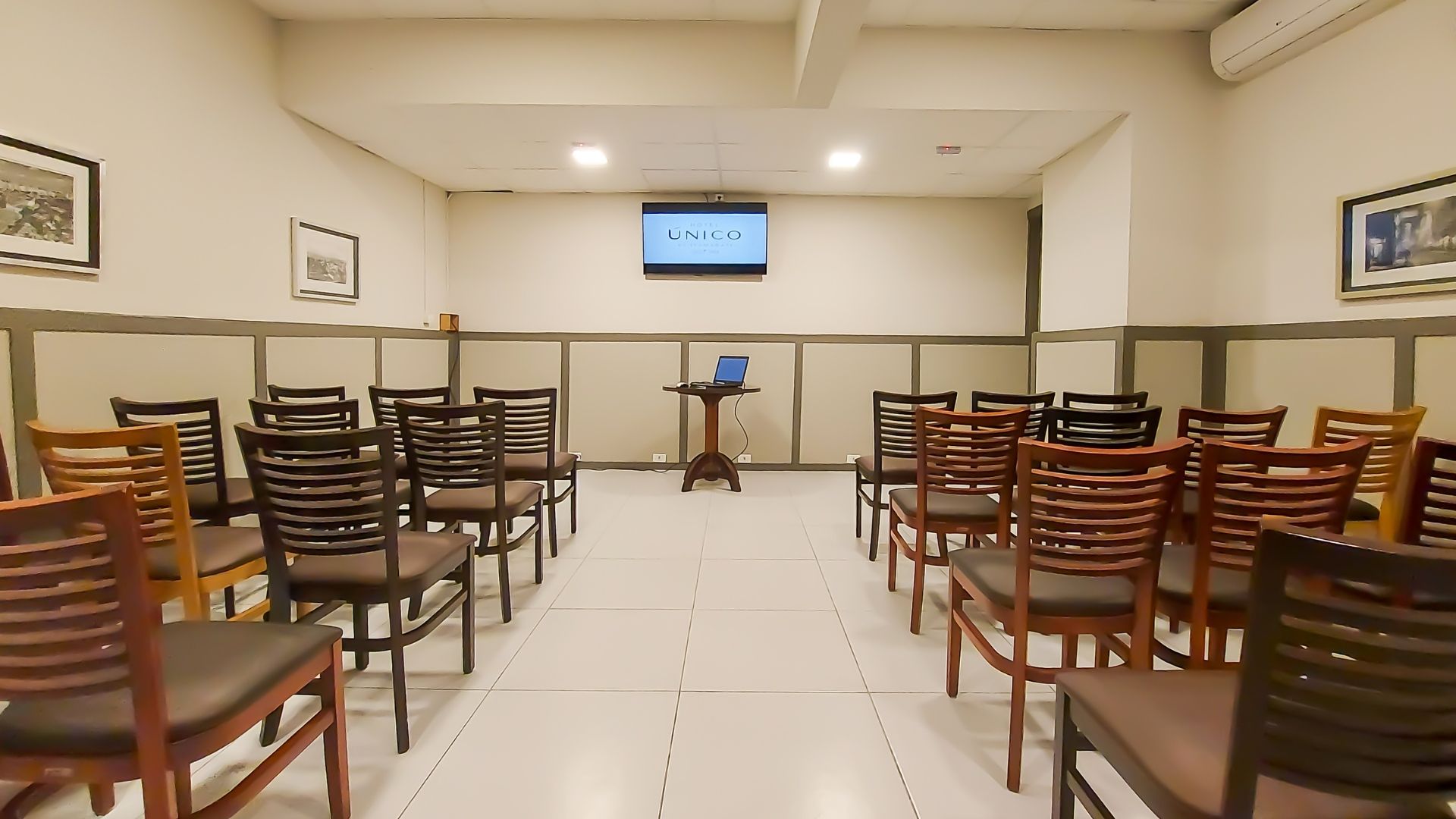 Uma sala com fileiras de cadeiras e uma televisão na parede.