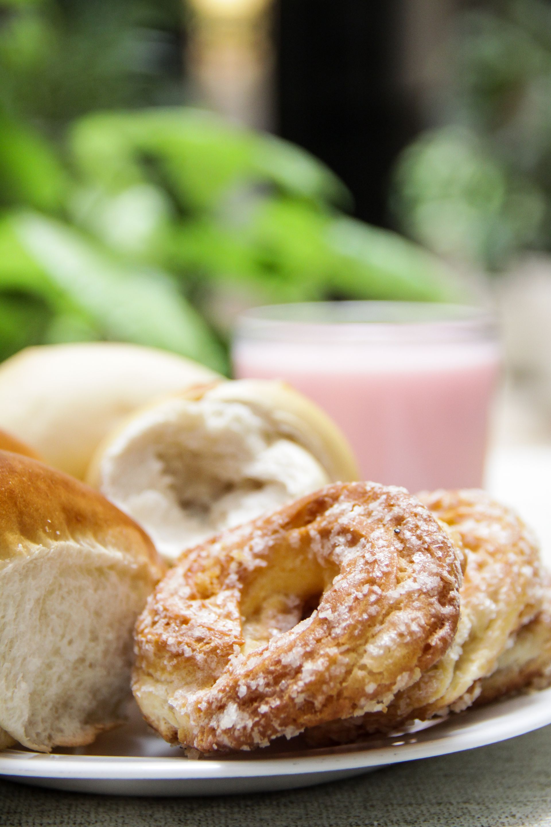Um prato de pão e donuts com um copo de leite ao fundo.