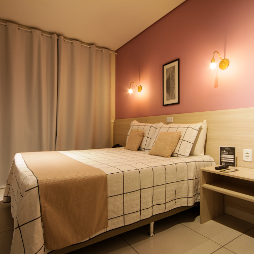Um quarto de hotel com uma cama king size e paredes rosa