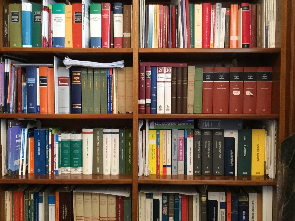 Scaffali pieni di libri di vari colori, titoli e dimensioni, in una libreria di legno.