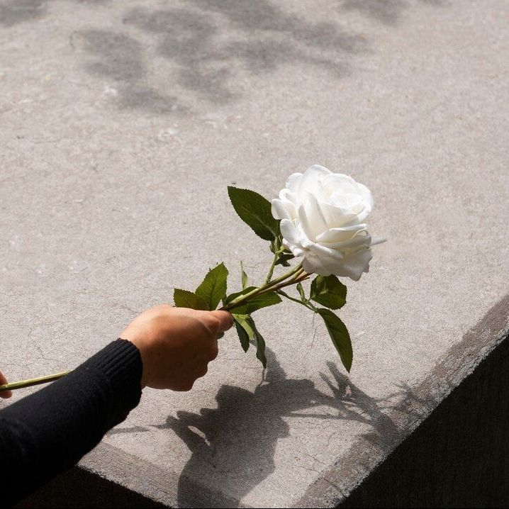 a woman in a black dress is holding a bunch of white flowers