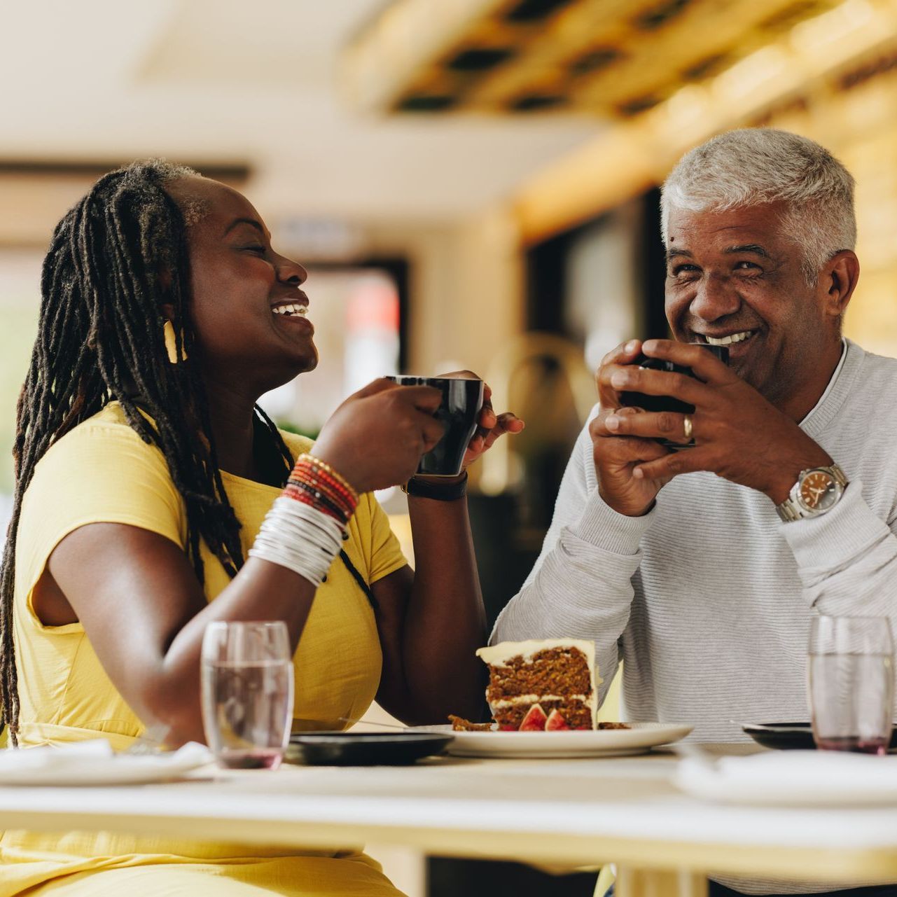 two people are sitting at a table drinking coffee