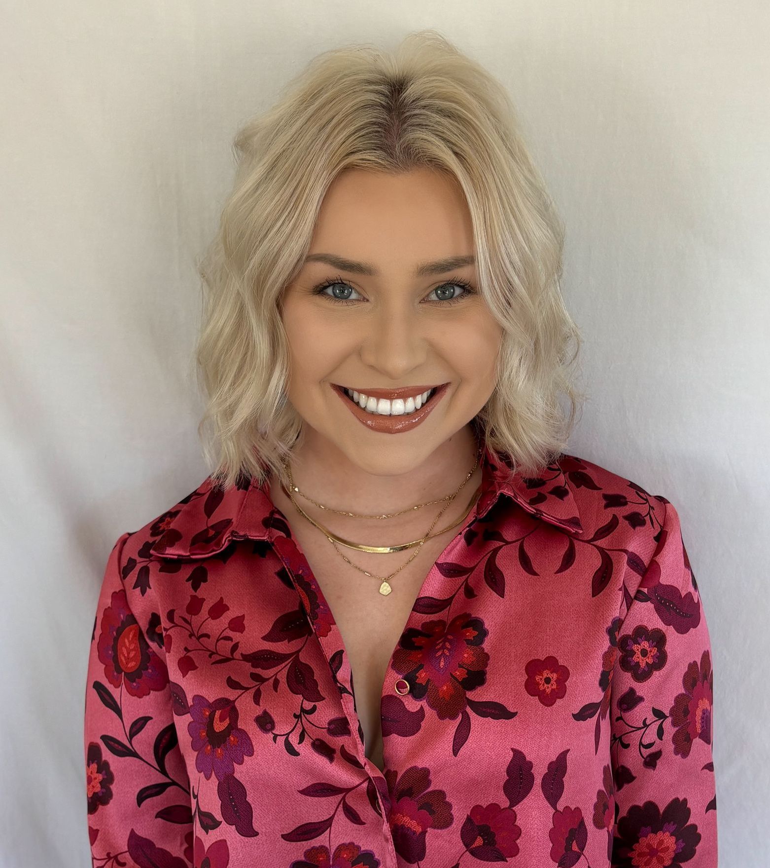 A woman in a pink floral shirt is smiling in a circle