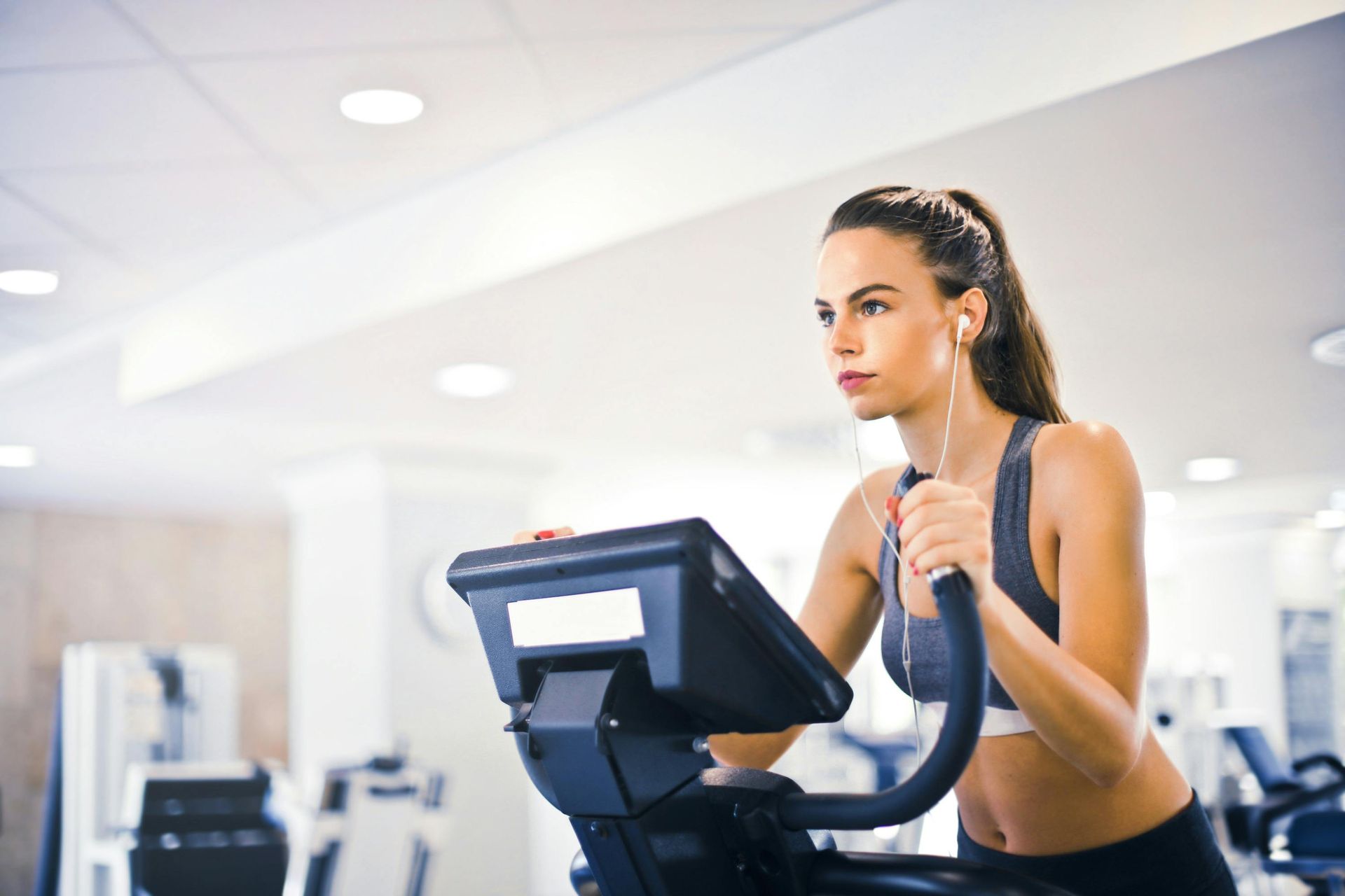 A woman is riding an exercise bike in a gym while listening to music.