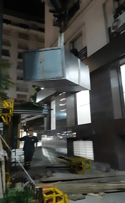 Una gran caja de metal está siendo levantada por una grúa.