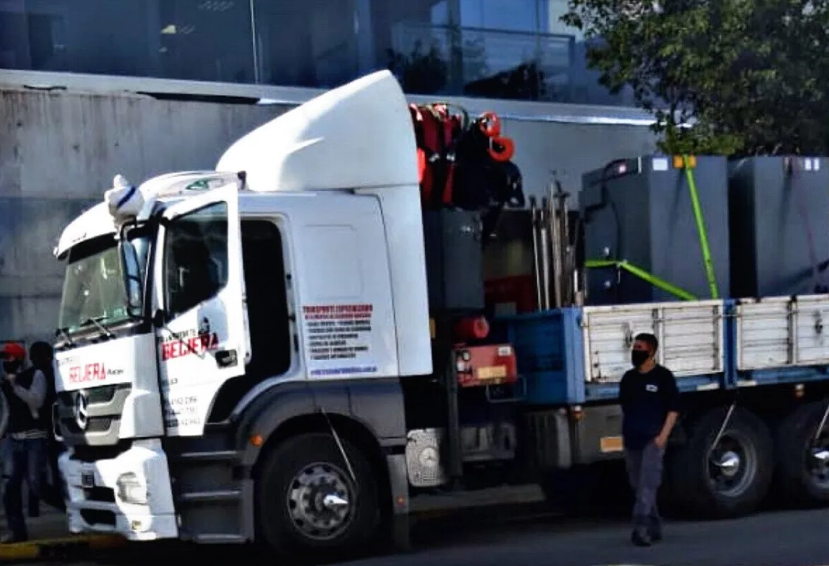 Un hombre está parado frente a un gran camión con una grúa en la parte trasera.
