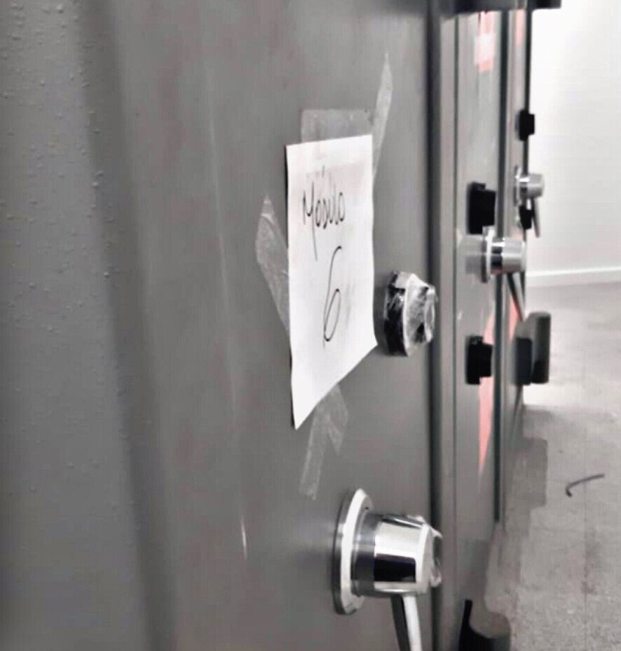 Un trozo de papel pegado al costado de una caja fuerte con el número 6 escrito en él