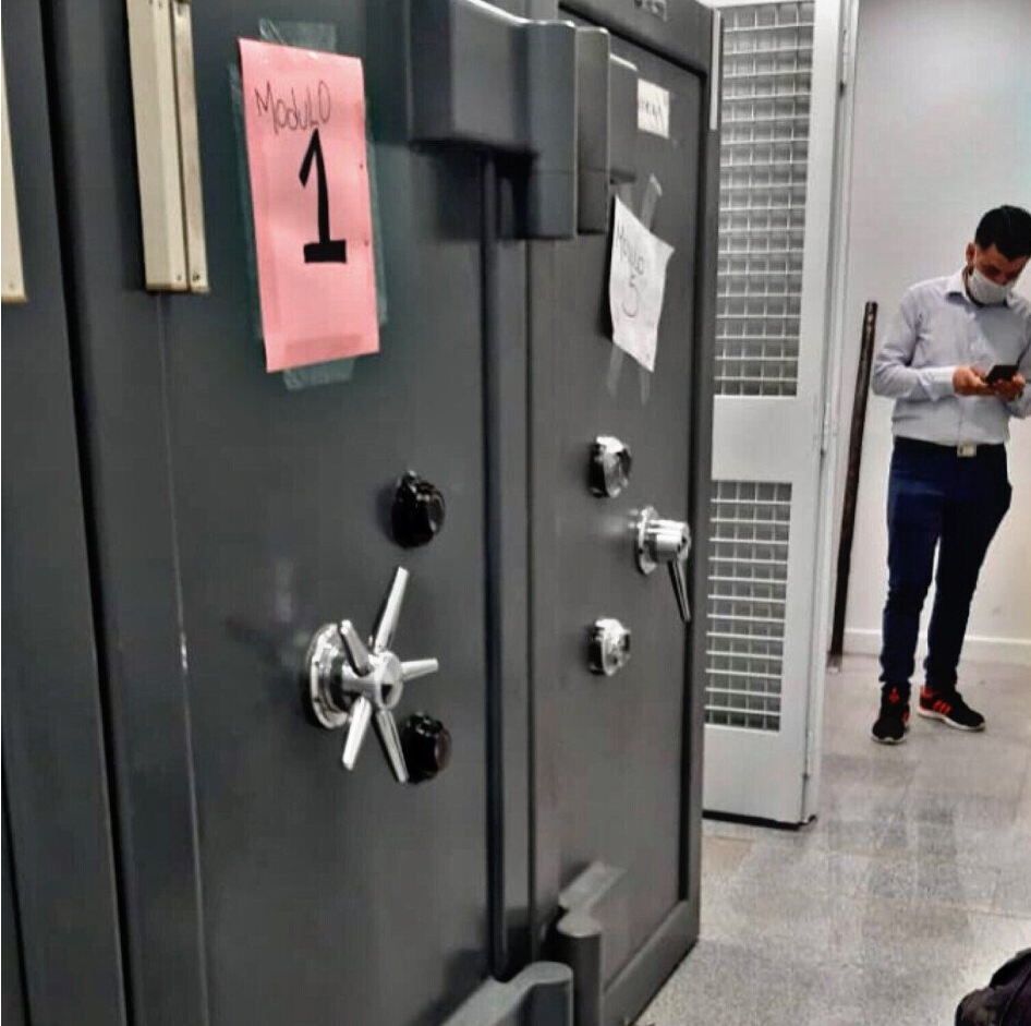 Un hombre de pie junto a una caja fuerte con el número 1.