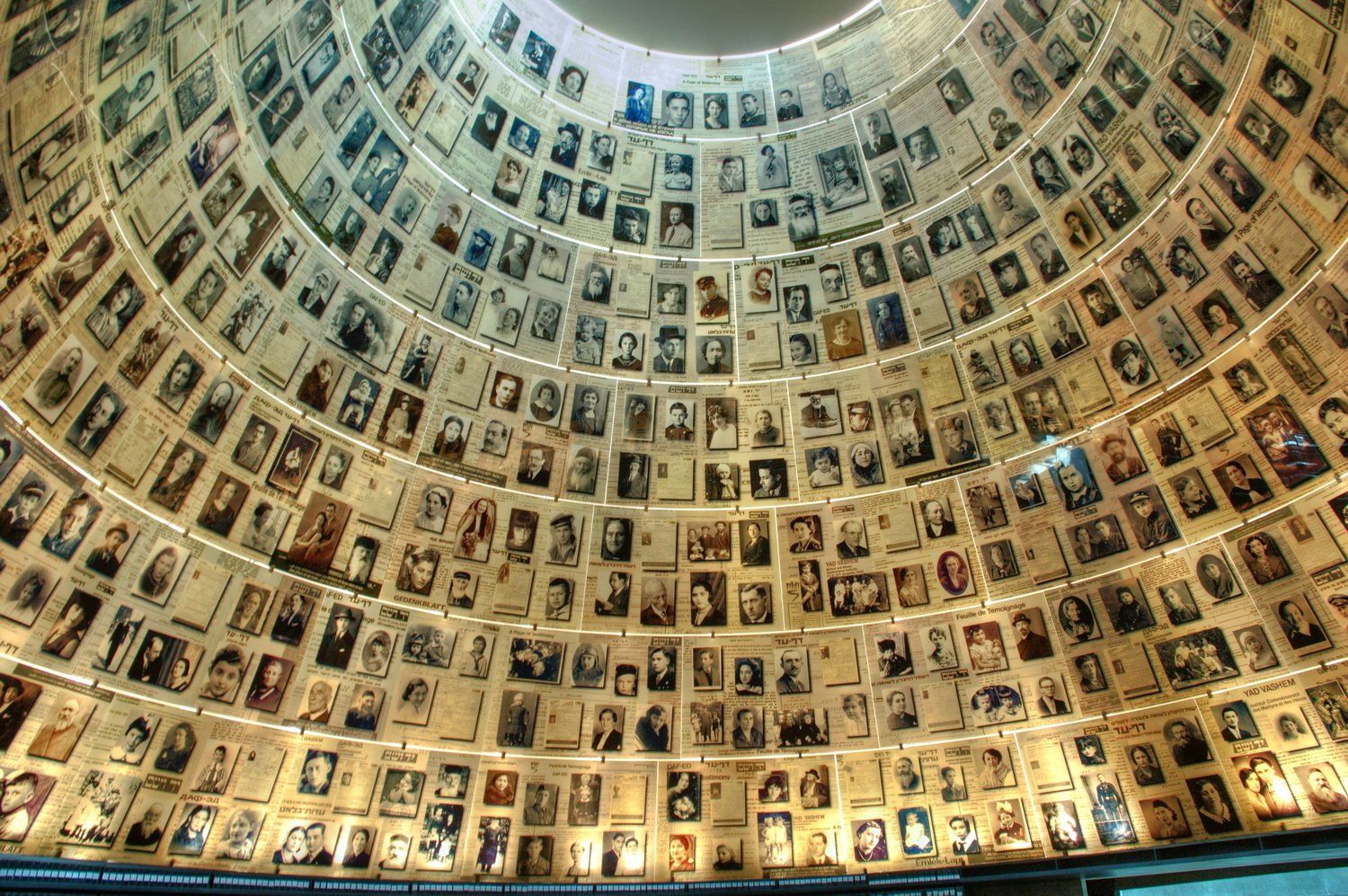 כיפה מלאה במאות תמונות של קורבנות השואה. הקירות מתעקלים כלפי מעלה, מוארים מהמרכז.