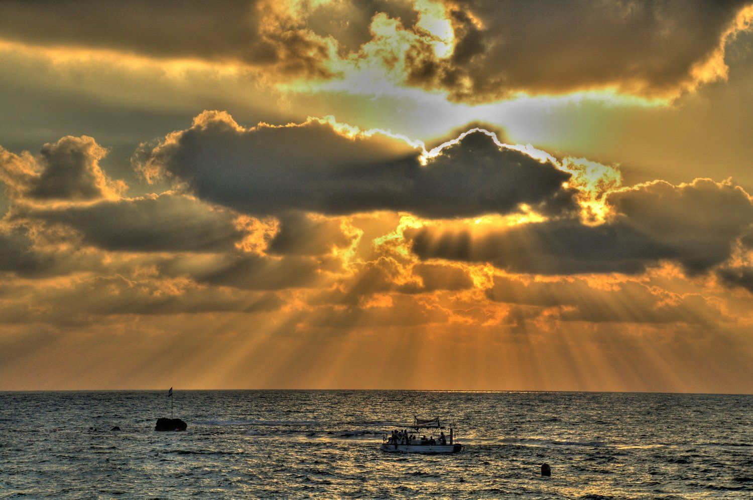 שקיעה מעל האוקיינוס עם עננים ואור שמש הזורחים דרכם, מאירים סירה.