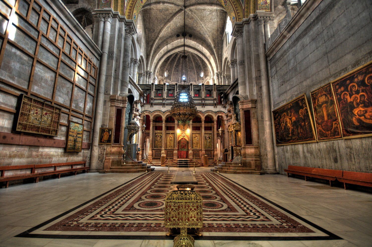 פנים כנסיית הקבר בירושלים: תקרות גבוהות, מזבח מעוטר, יצירות אמנות ושורות של ספסלים.