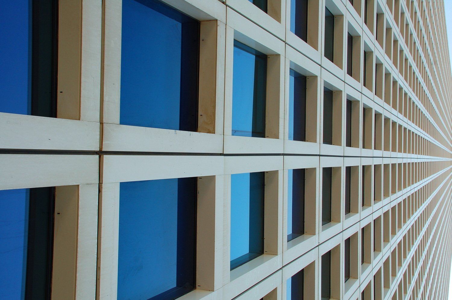 חזית בניין עם רשת של חלונות כחולים ומסגרות לבנות.