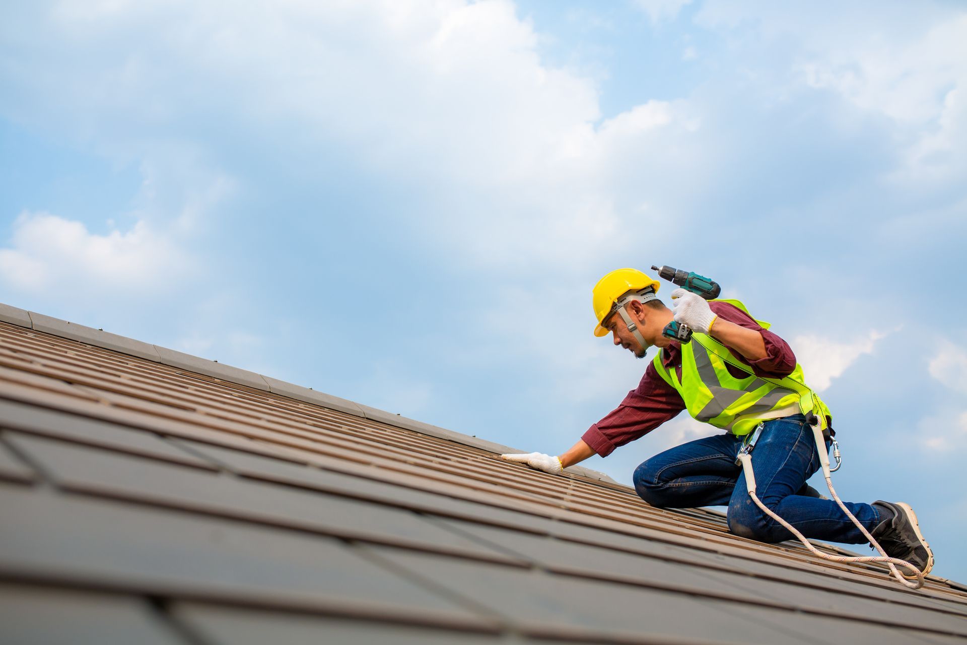 Worker On Roof Holding A Drill — Belleville, MI — Discount Roofing
