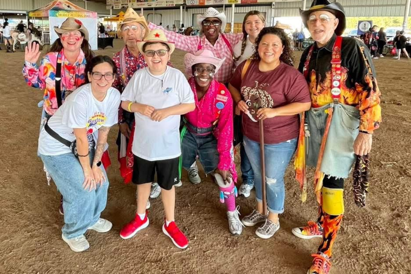 Group of people smiling and posing together outdoors in a barn-like setting, some holding canes.