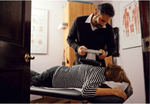 Physical therapist performing hands-on treatment for a patient lying on a treatment table.
