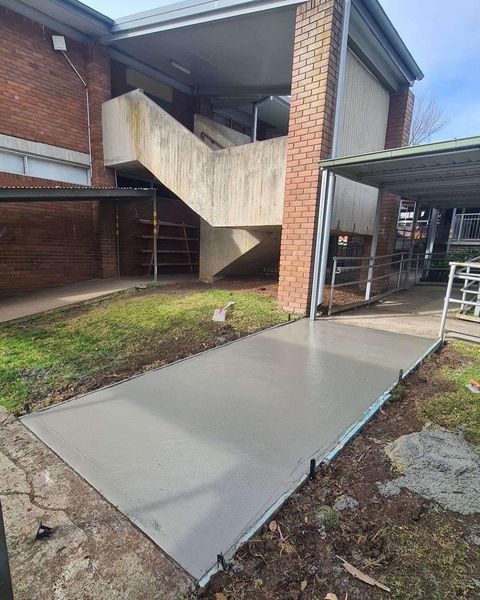 A Concrete Walkway Is Being Built in Front of A Brick Building — Illawarra Resurfacing Pty Ltd in Austinmer, NSW