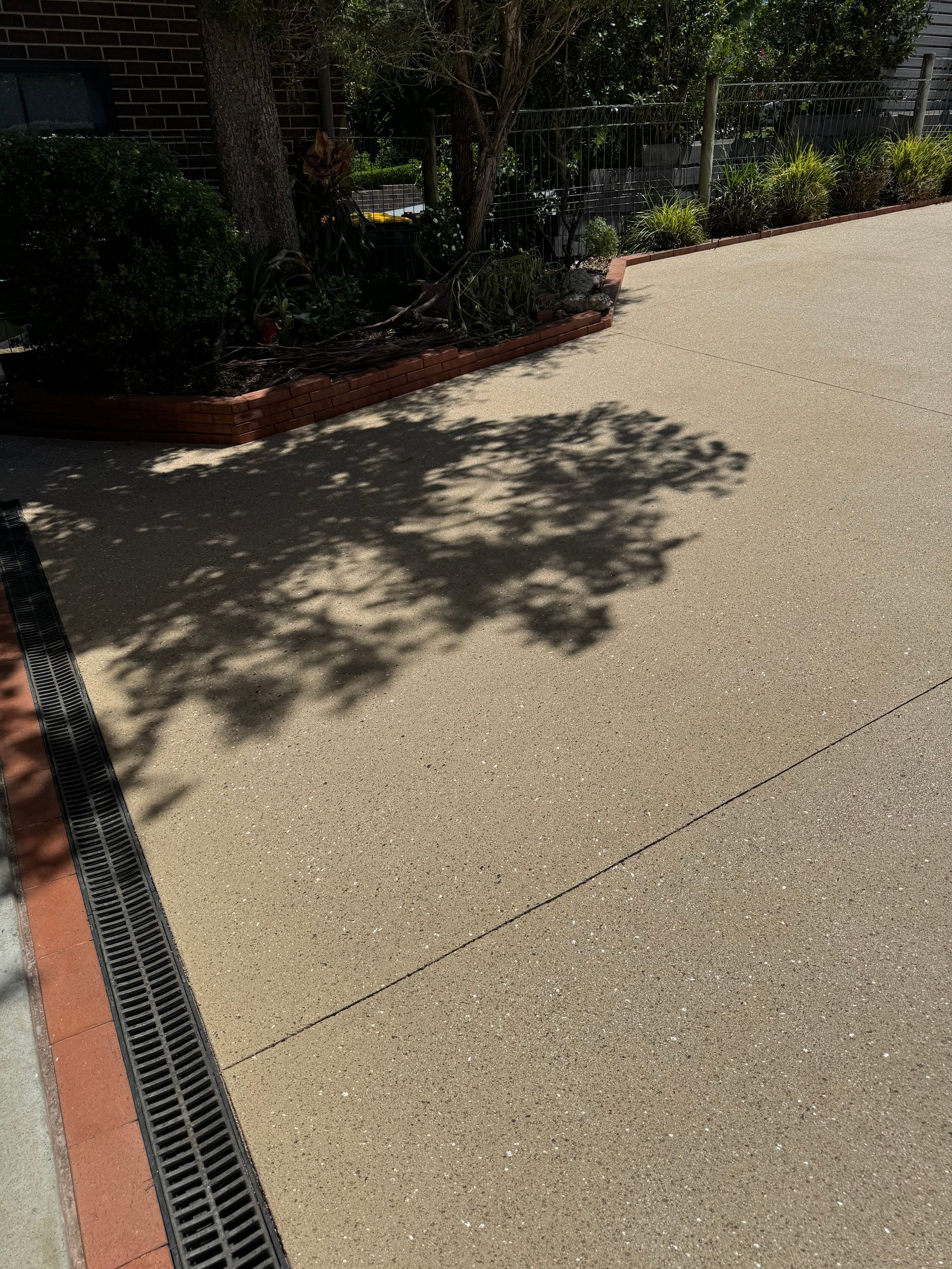 A Concrete Driveway Leading to A House with A Garage — Illawarra Resurfacing Pty Ltd in Balgownie, NSW