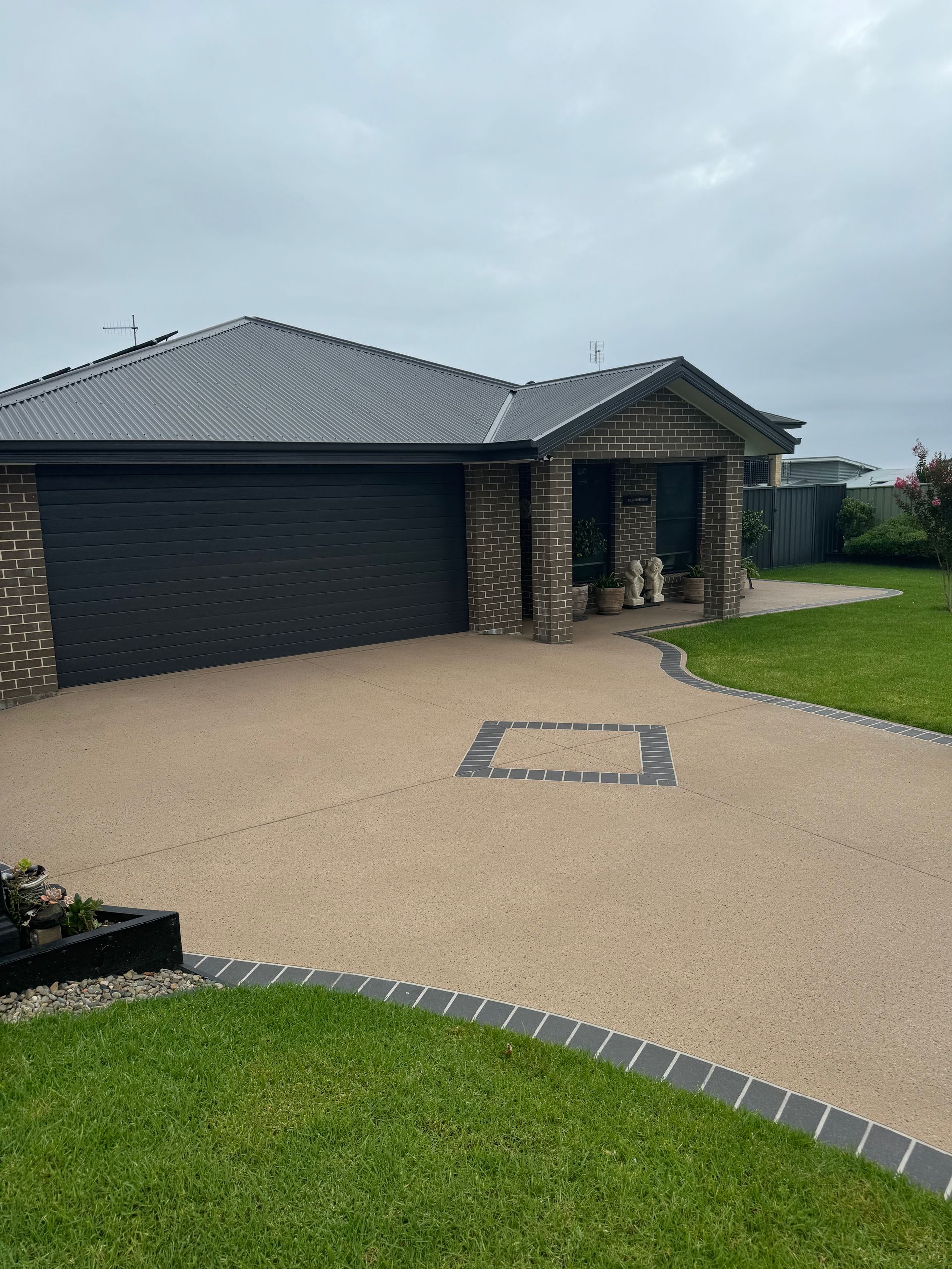A Concrete Driveway Leading to A House with A Garage — Illawarra Resurfacing Pty Ltd in Shellharbour, NSW