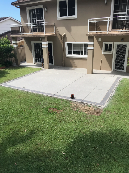 A Concrete Patio Is Being Built in The Backyard of A House — Illawarra Resurfacing Pty Ltd in Balgownie, NSW