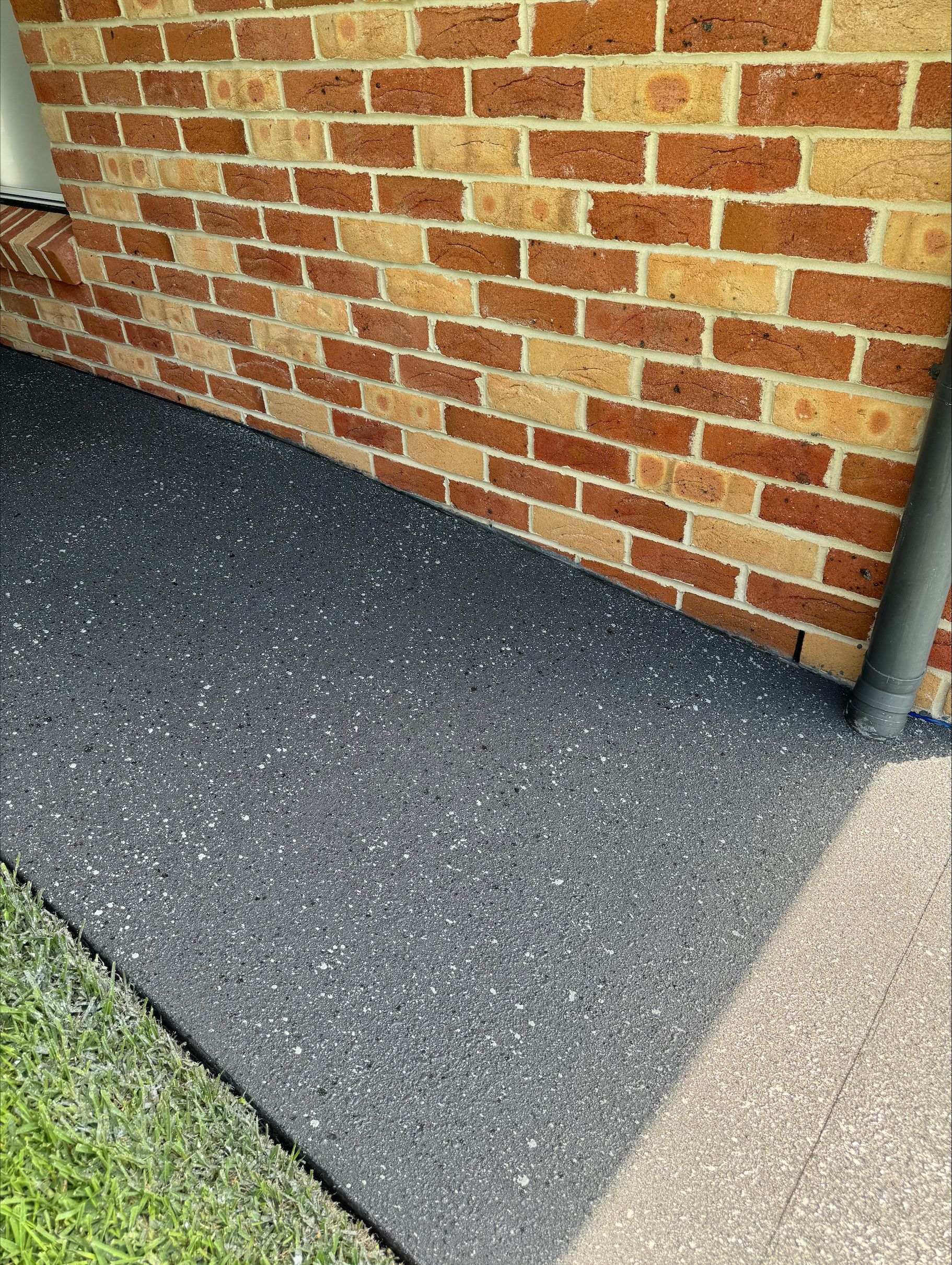 Decorative Concrete Resurfacing In Front of A Brick House Wall — Illawarra Resurfacing Pty Ltd in Balgownie, NSW