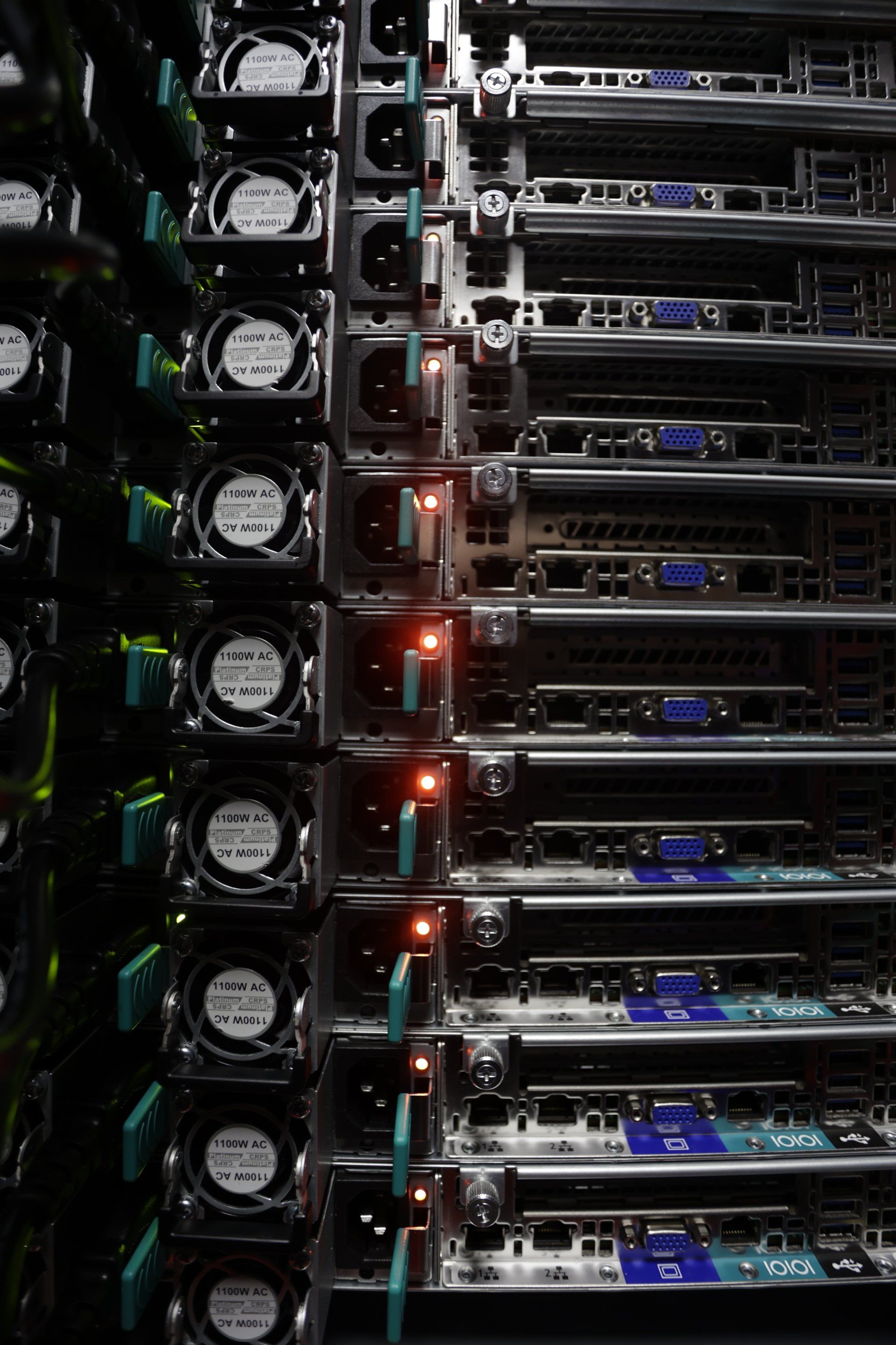 Rows of stacked computer servers with fans, lights, and cables in a data center.