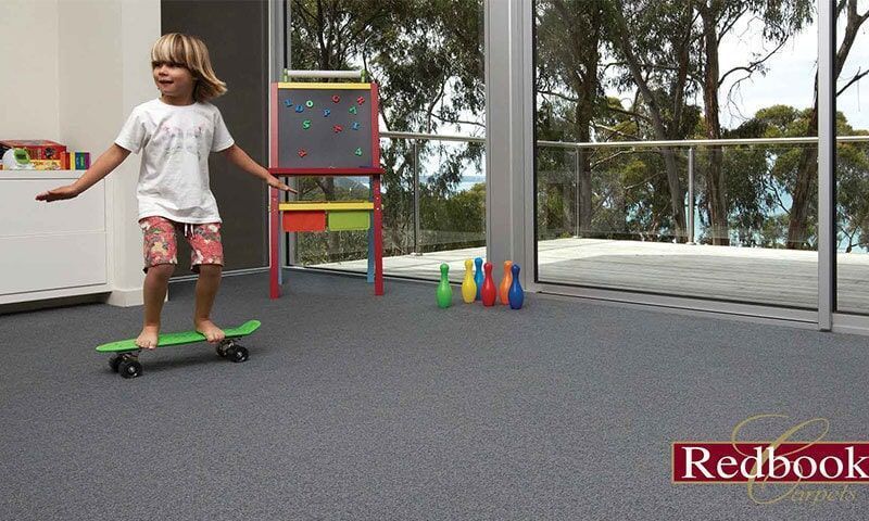 A Little Boy is Riding a Green Skateboard on a Grey Carpet — Floor Zone Gympie In Gympie, QLD