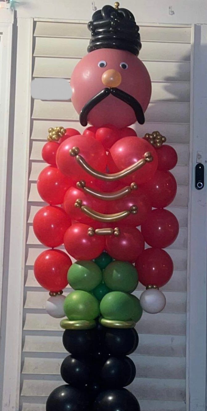 nutcracker made out of red green and black balloons with gold accents