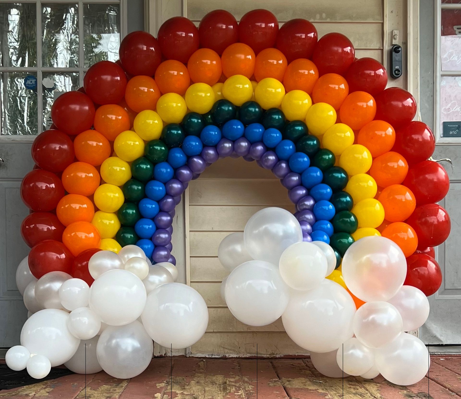 A rainbow made out of balloons is in front of a door