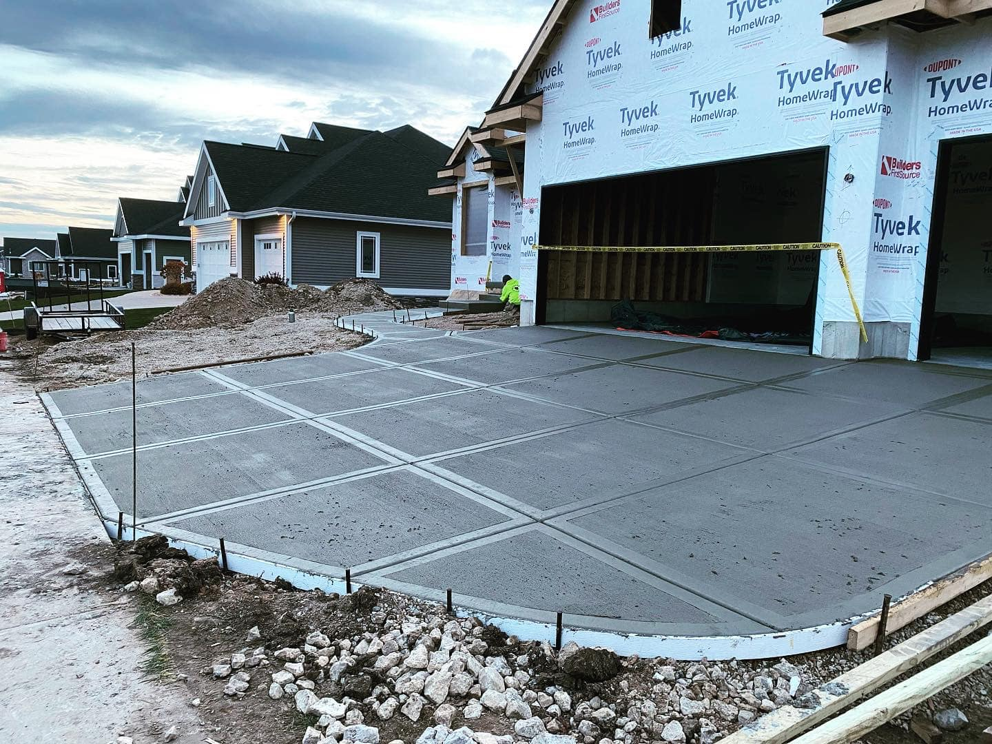 New concrete driveway in front of a house under construction; curved edges, scored design.