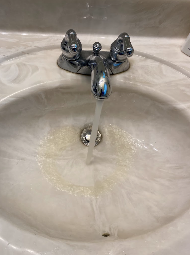 Bathroom sink with running faucet and water draining into the basin
