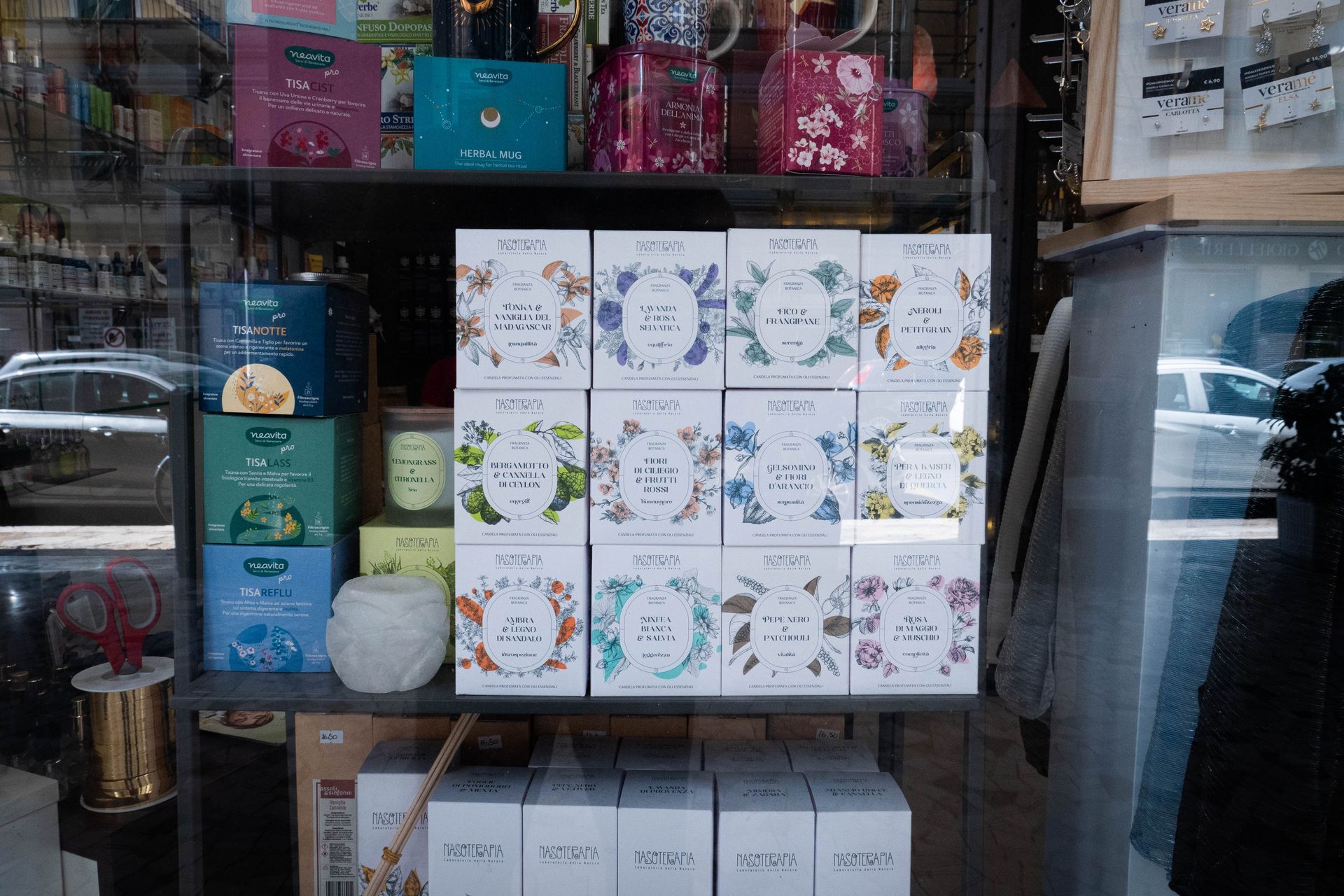 Esposizione in vetrina di varie scatole da tè, scaffali e oggetti decorativi.