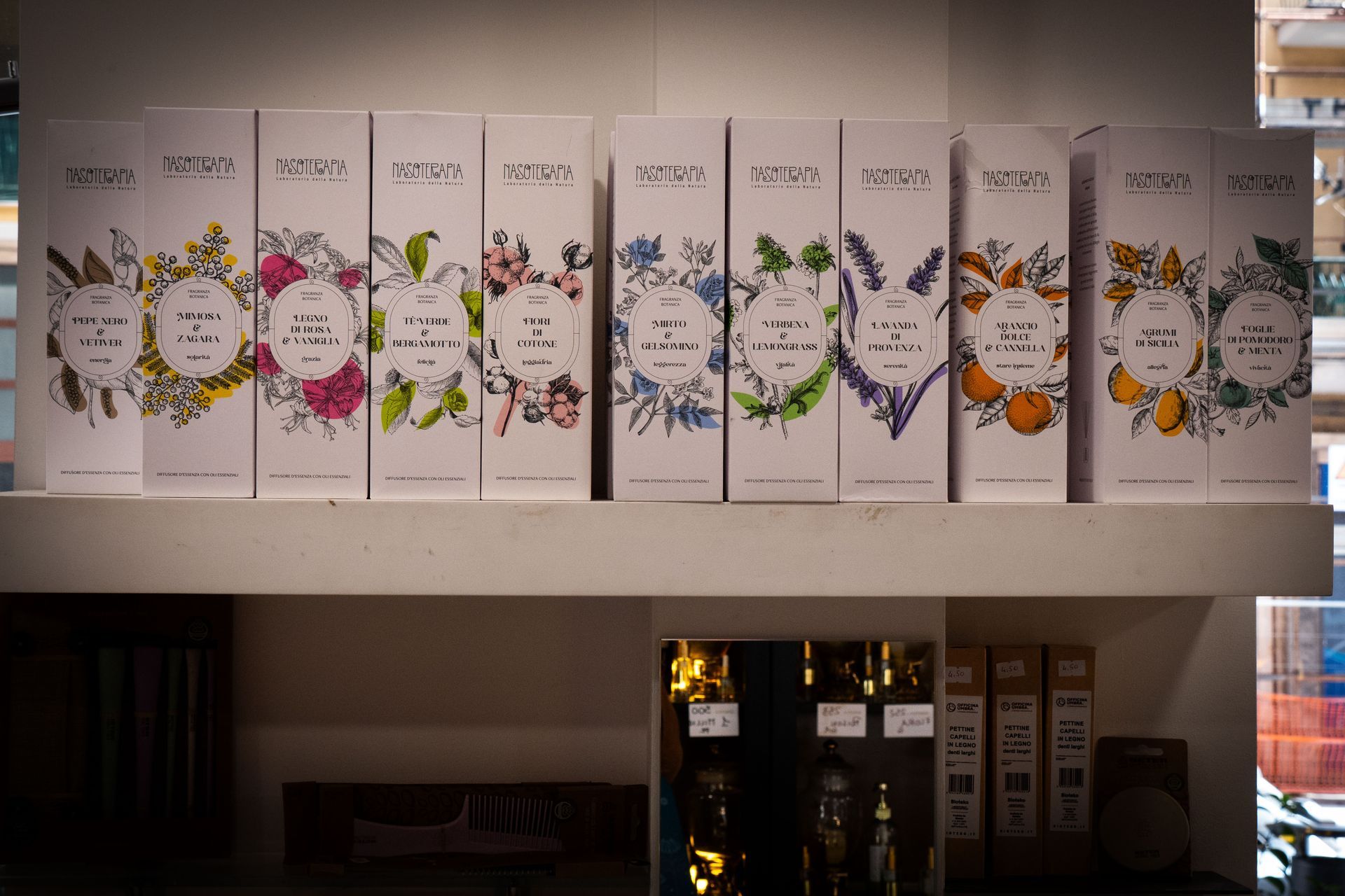 Fila di scatole colorate con motivi floreali su uno scaffale, probabilmente per i prodotti di un negozio.