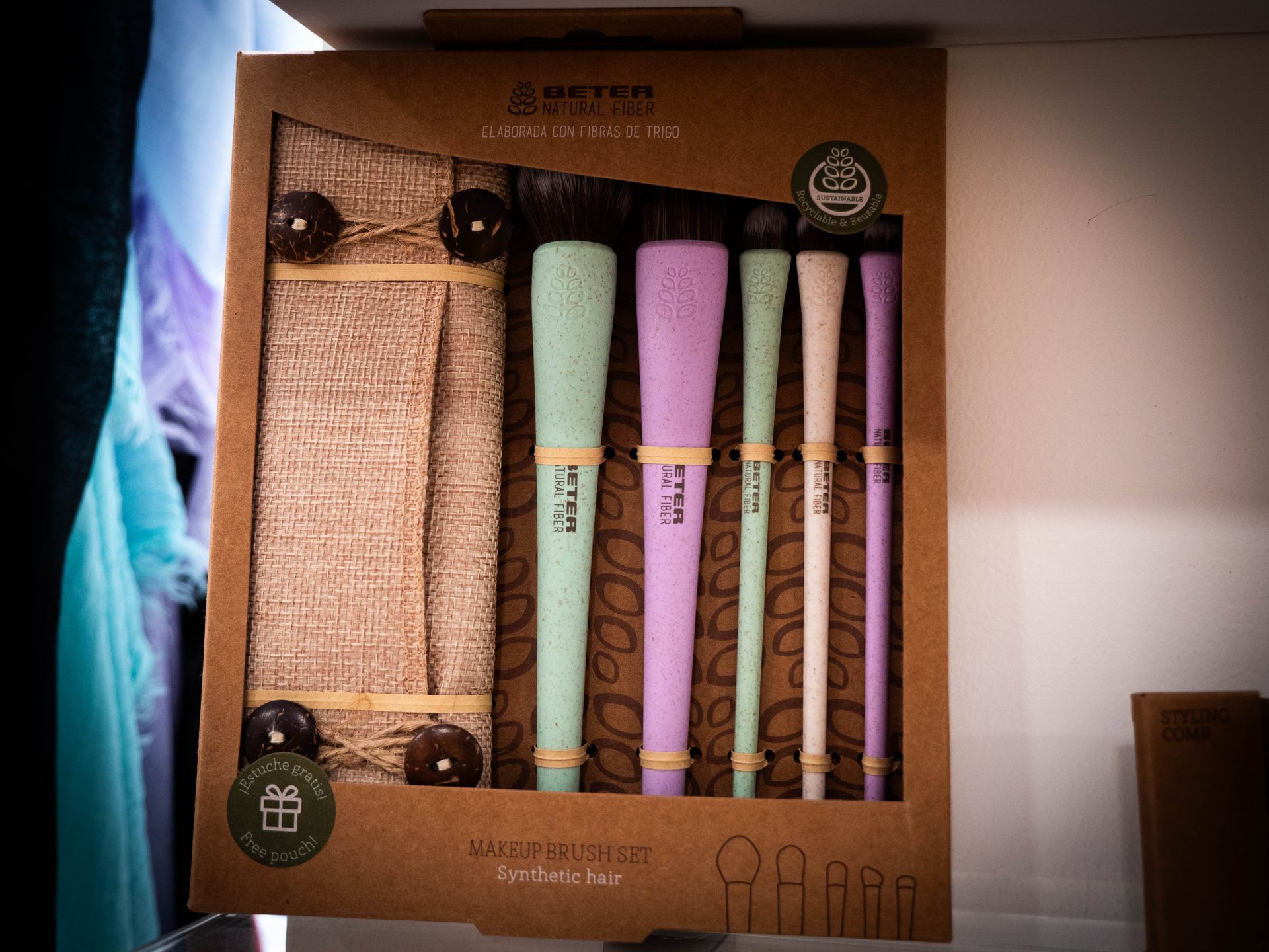 Set di pennelli per il trucco in una scatola di cartone, con manici color pastello e supporto con texture in tela di iuta.