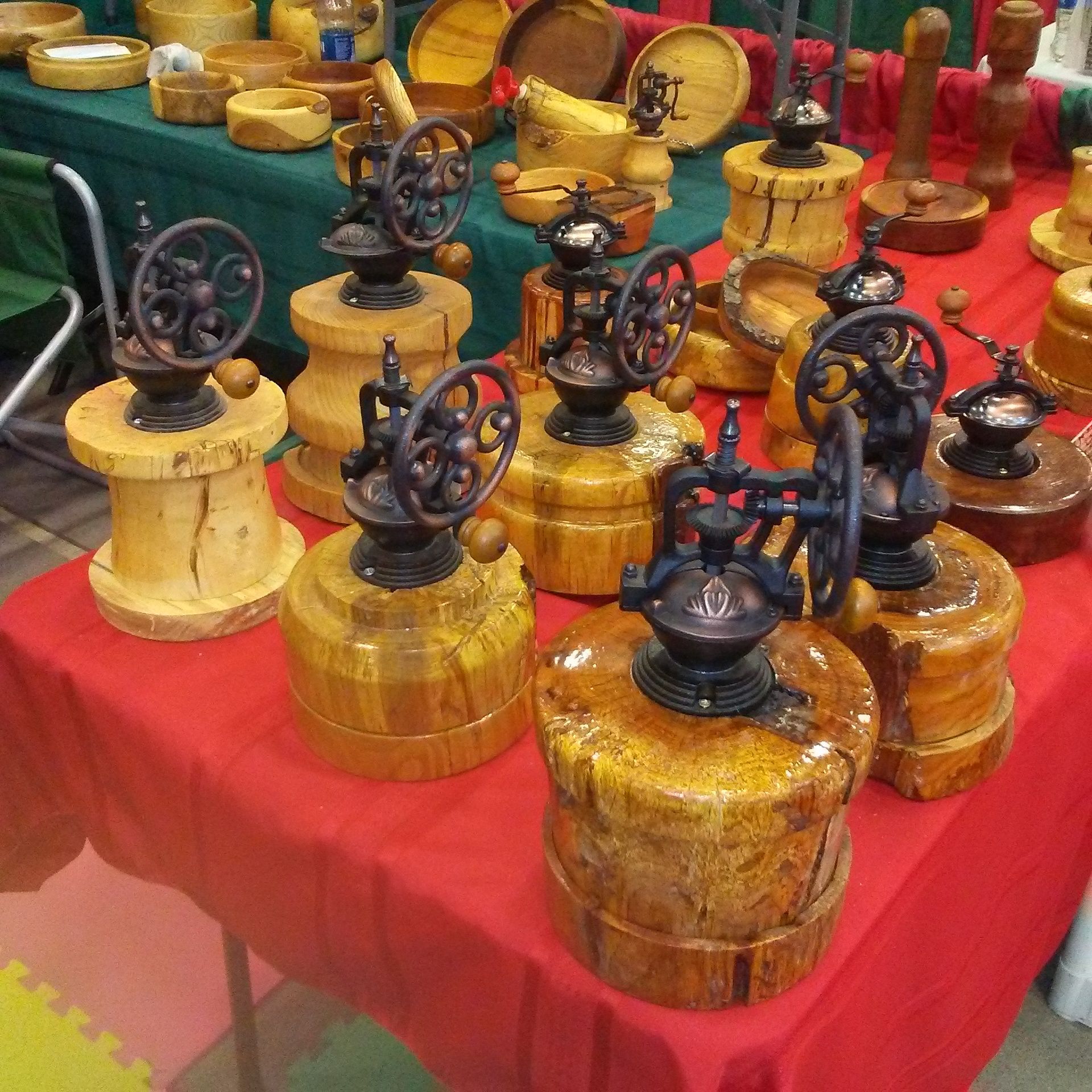 Display of wooden bases with antique coffee grinders, red tablecloth.