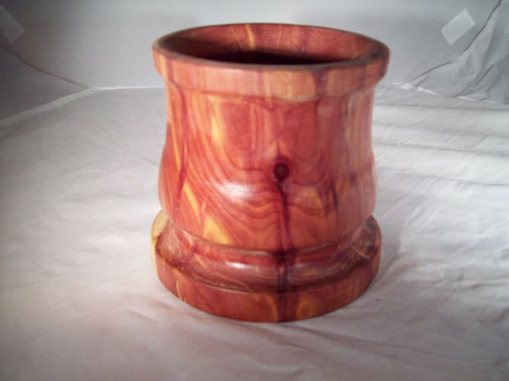 Red and yellow wooden vase, with rounded midsection and base, against a white background.