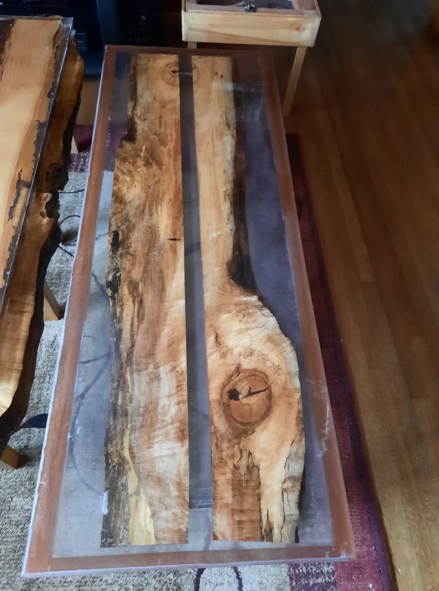 Coffee table with two wooden planks and clear epoxy resin filling the gaps, brown trim.