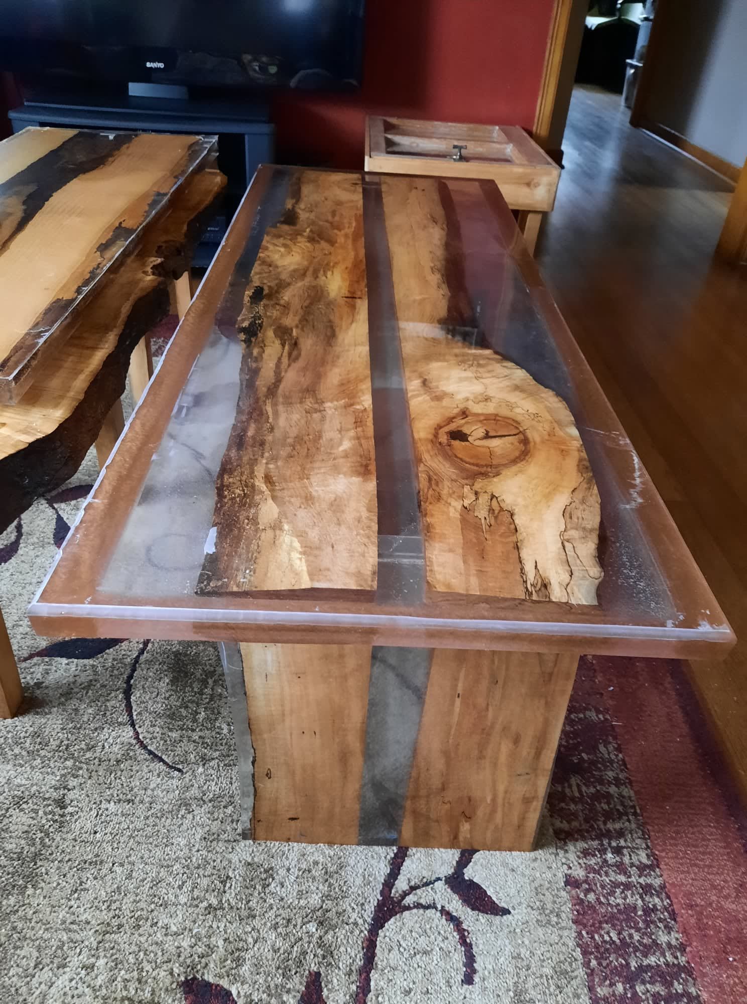 Wooden mushroom-shaped side table with blue-rimmed top, sitting on a wood floor, near a broom.